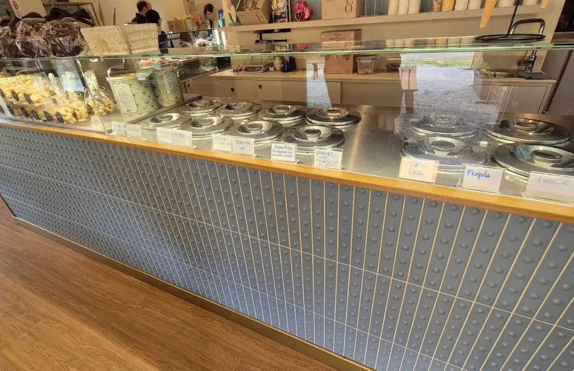Il bancone azzurro della gelateria con i pozzetti dei gusti